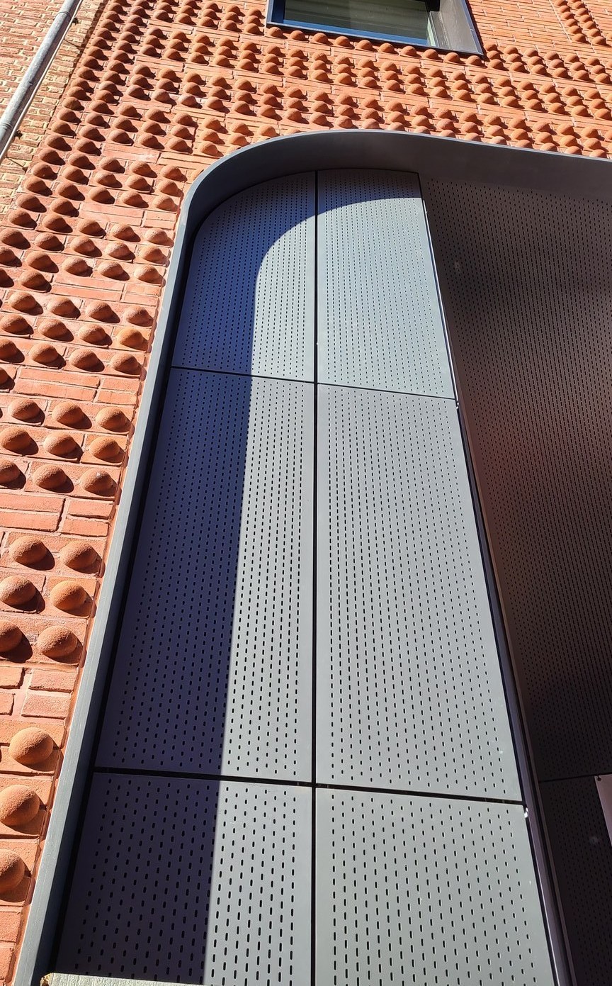 Facade — perforated metal canopy and terracotta brick